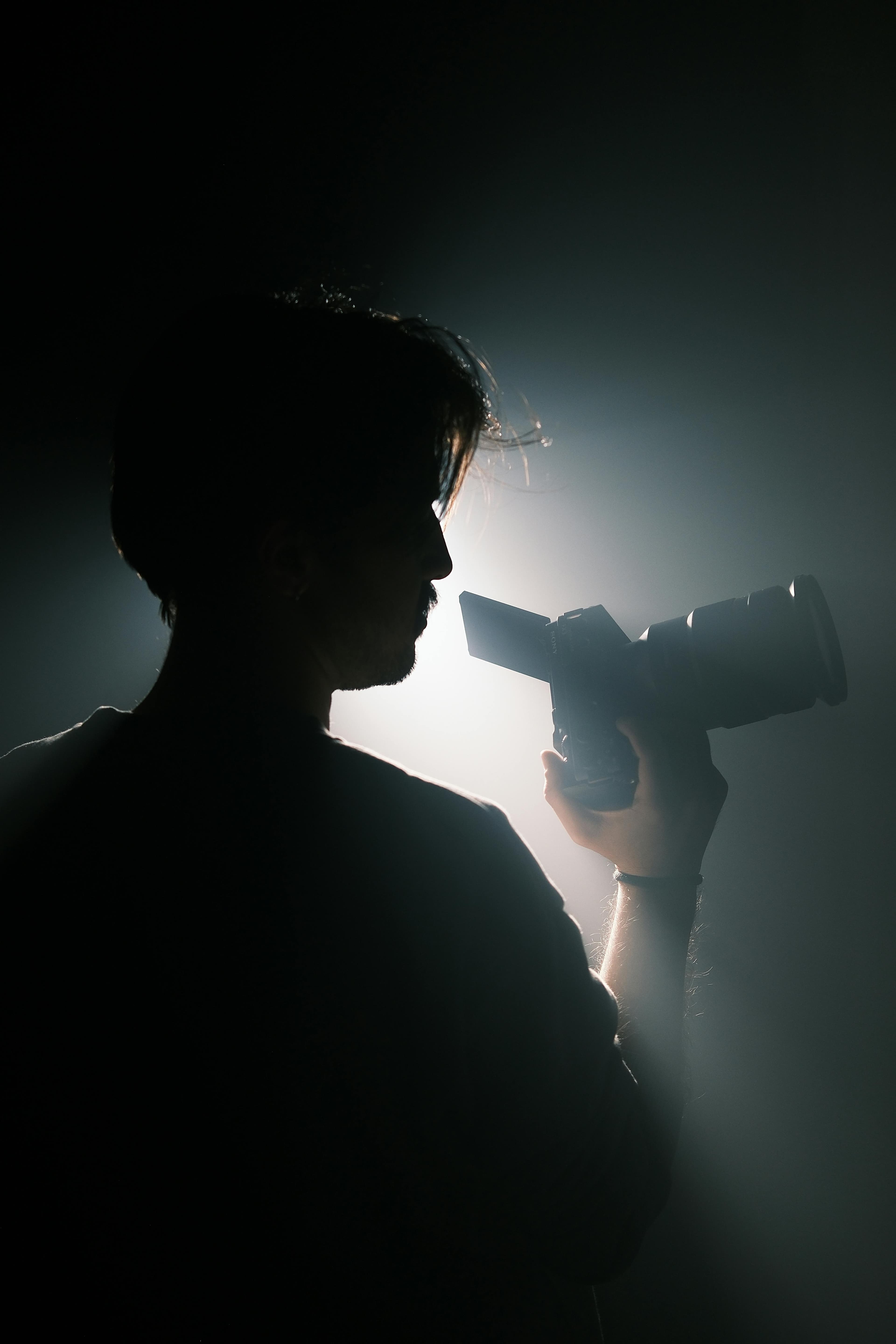 Silhouet van een filmmaker met camera tegen fel tegenlicht.