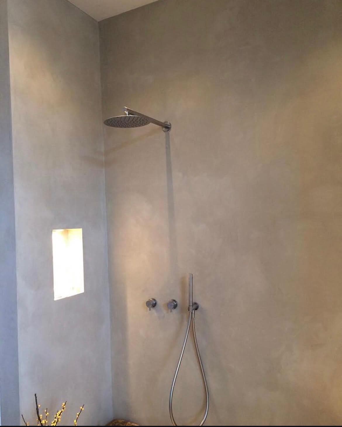 Badkamer met rustige betonlook wandafwerking en strakke douchehoek.